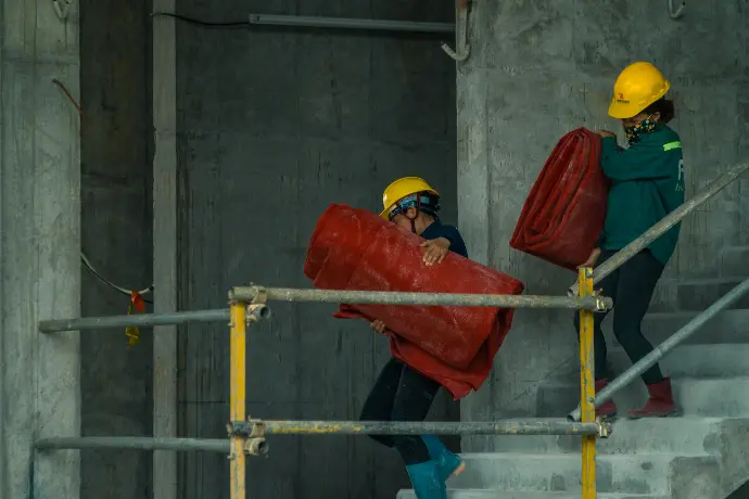 man in orange hard hat holding red plastic bag